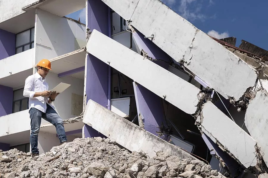 Natural-Disaster-Insurance-Engineer-Looking-Over-the-Rubble-with-an-iPad-in-Hand