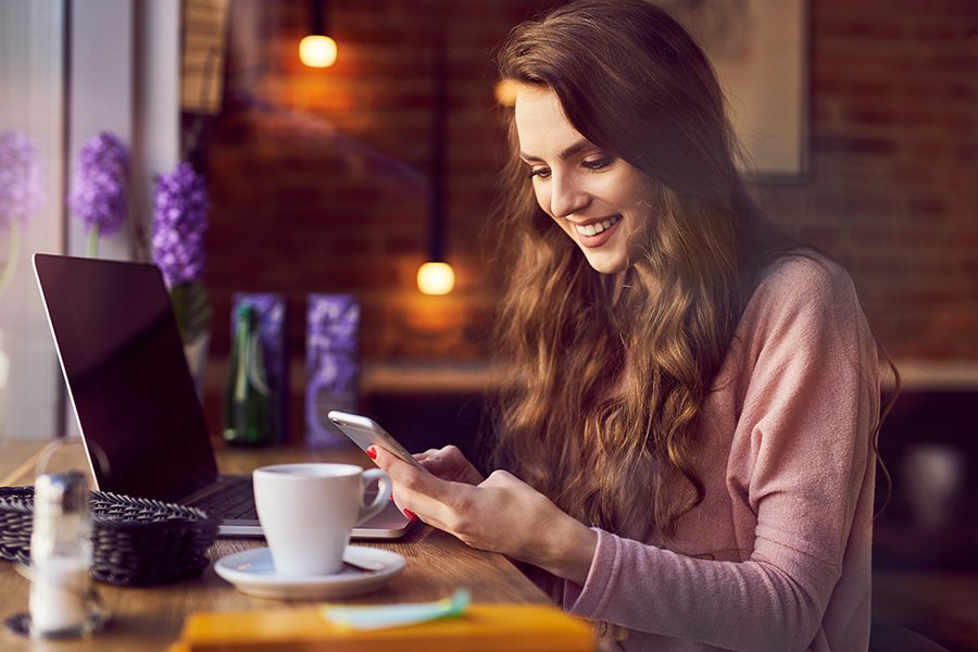 Video Library - Young Woman Smiling and Looking At Her Phone In A Local Coffee Shop