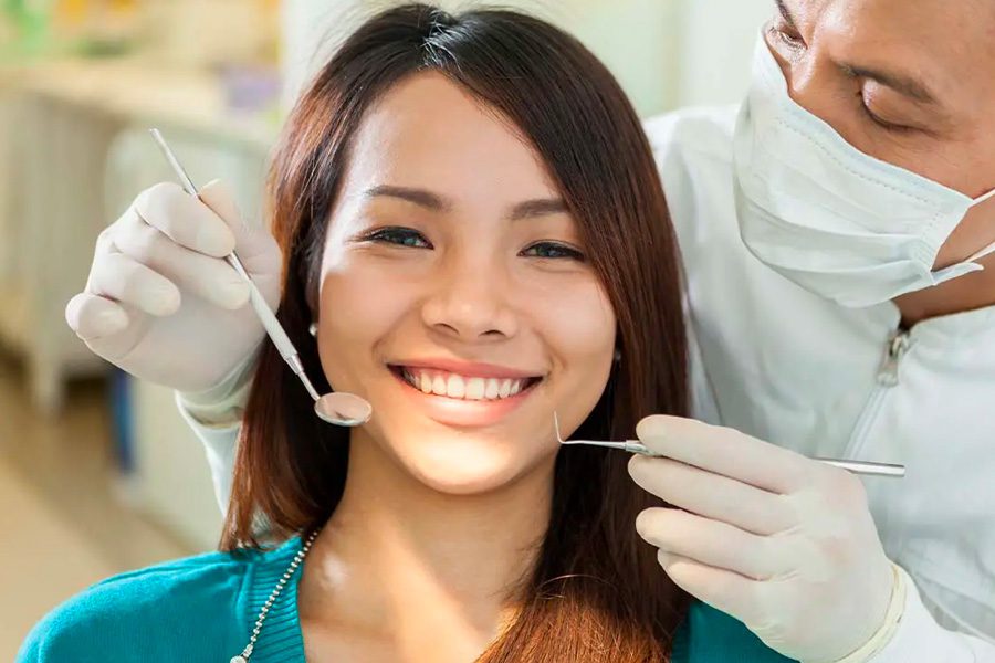 Individual Dental Insurance - Close-up Portrait of a Young Smiling Woman While Waiting in Dentist Chair for a Teeth Cleaning by Dentist