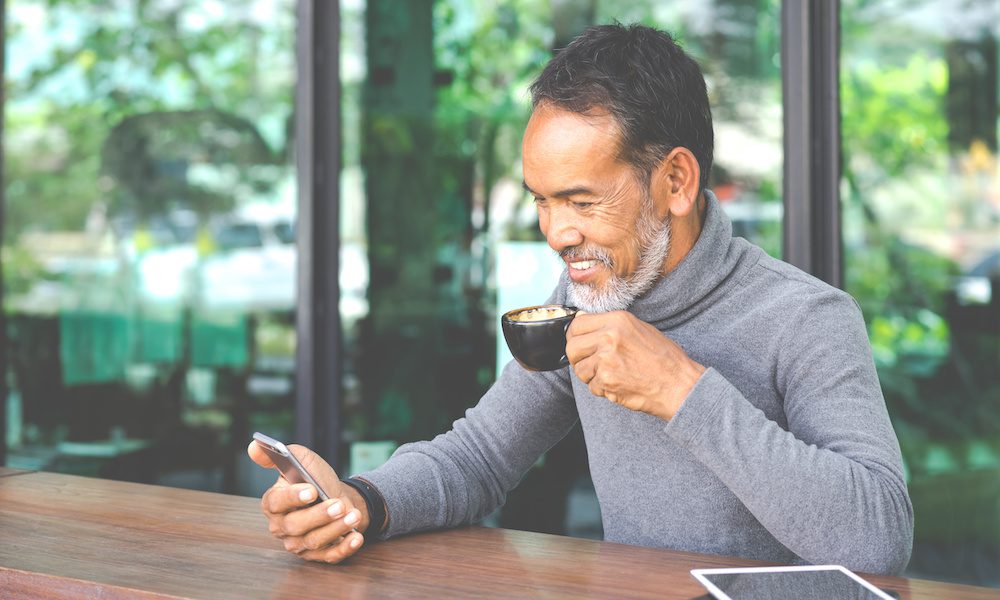 Securing Your Future/ Life Insurance for Individuals Over 50 - An older gentleman drinking coffee while looking at his phone
