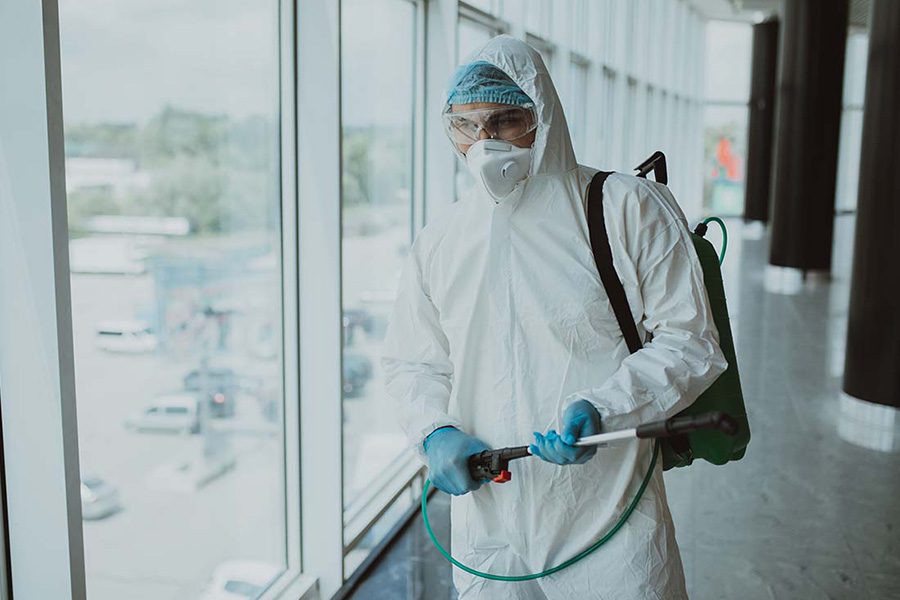 Abatement Contractor Insurance - Abatement Worker in a Protective Suit with Mask Sprays for Mold in the Office