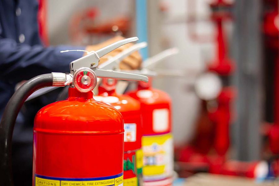 Fire Protection Contractor Insurance - Focus on Fire Extinguishers With an Engineer Checking Industrial Fire Control System to Ensure Readiness in the Event of a Fire