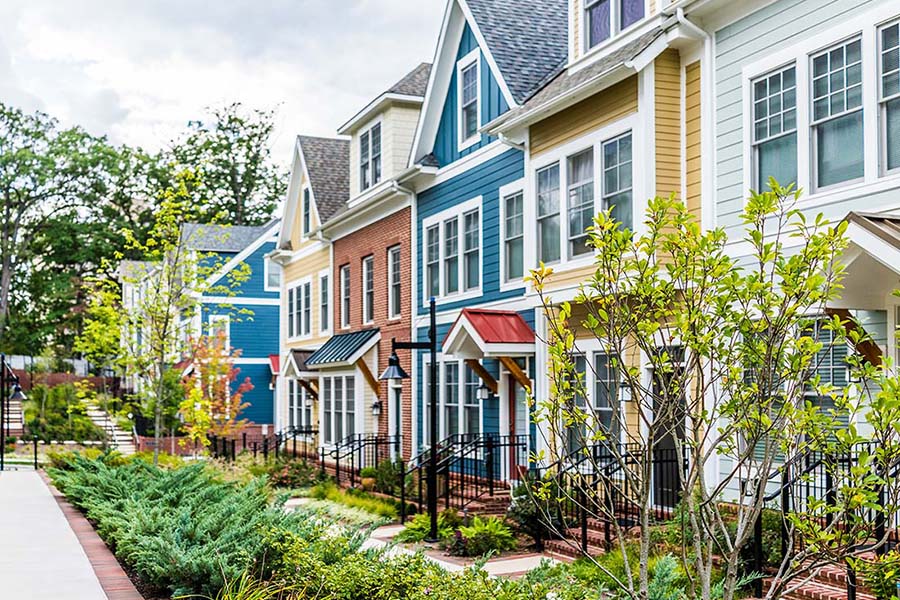 Homeowners Association Insurance - Row of Colorful, Red, Yellow, Blue, White, and Green Painted Residential Townhouses With Brick Patio in the Summer